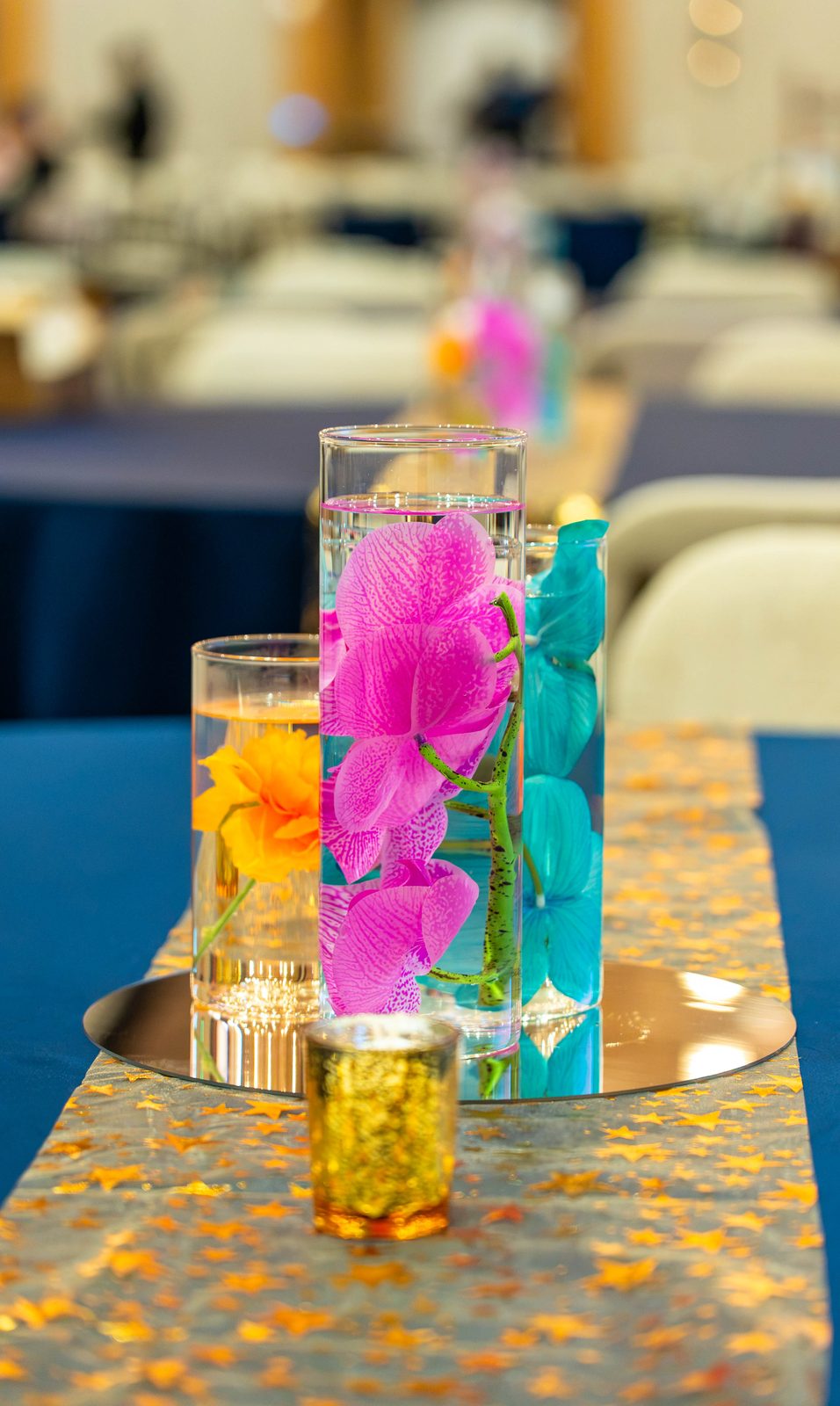 Orchid centerpiece on a gold sequin runner with rows of navy tables behind, PMI Washington DC Chapter Awards Gala, JW Marriott Reston, Virginia