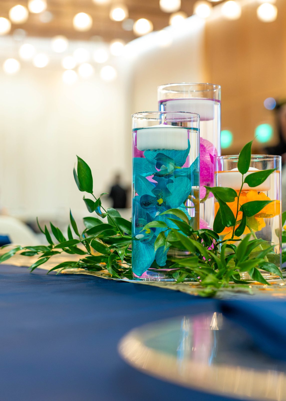 Close-up of greenery and floating-candle cylinders on navy linen at the PMI Washington DC Chapter Awards Gala, JW Marriott Reston, Virginia
