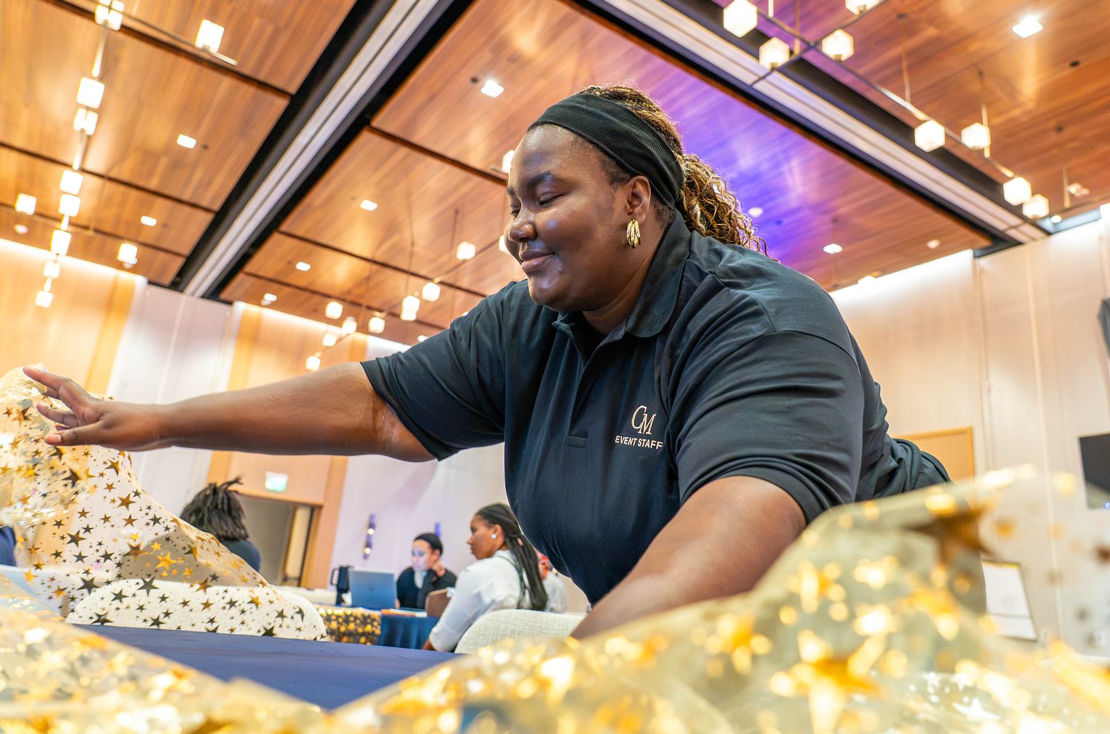 Creative Motion Events team member laying a gold star runner on a navy table during setup for the PMI Washington DC Chapter Awards Gala, JW Marriott Reston, Virginia