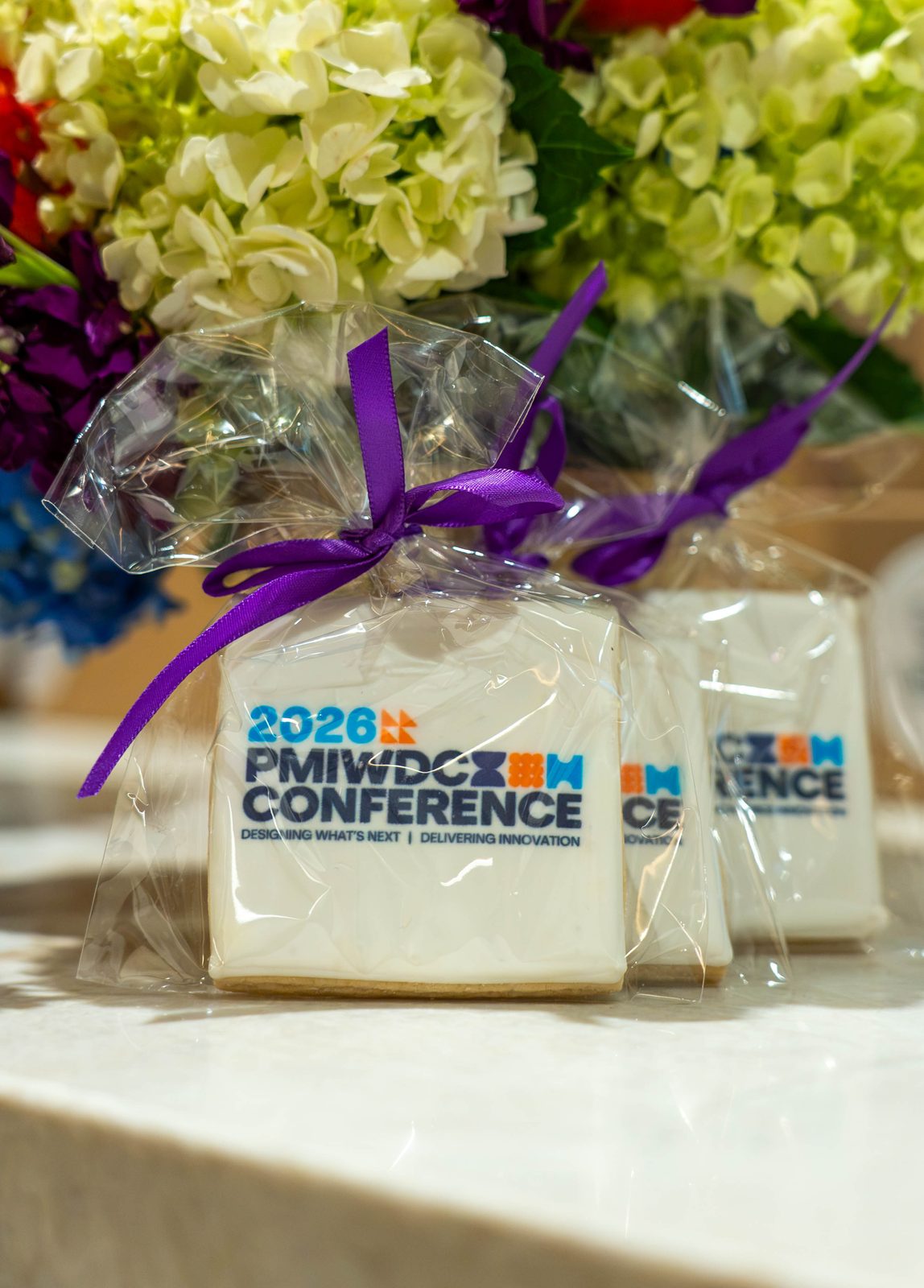 Row of 2026 PMIWDC Conference logo cookies with purple ribbons and hydrangeas, PMI Washington DC Chapter Awards Gala, JW Marriott Reston, Virginia
