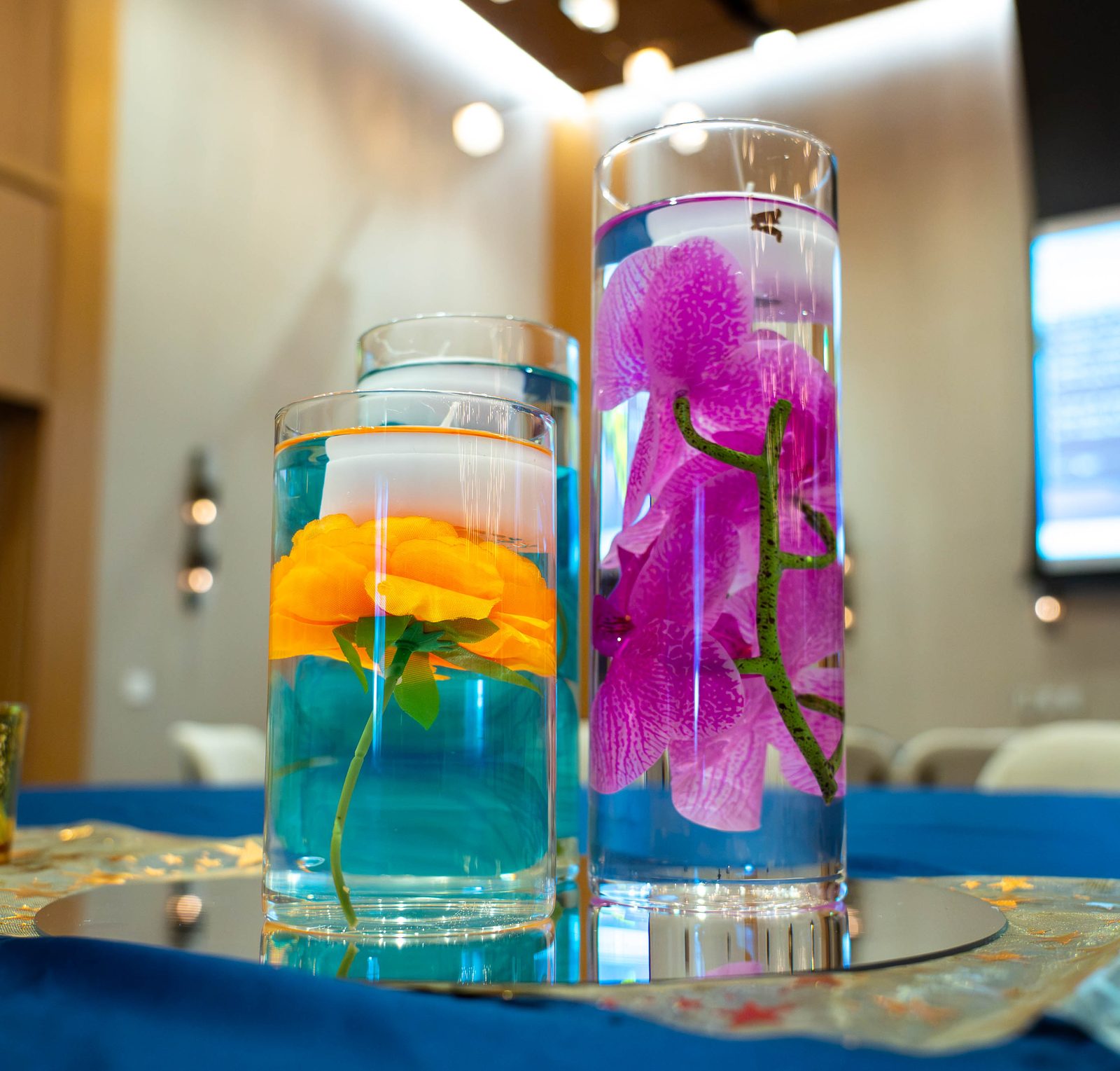 Close-up of orchid and orange-bloom cylinder centerpiece on a mirror base at the PMI Washington DC Chapter Awards Gala, JW Marriott Reston, Virginia