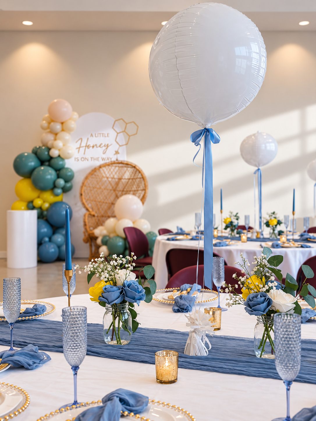 Baby shower table with dusty-blue decor, a teal, yellow, and cream balloon arch, and an A Little Honey is on the way sign — Creative Motion Events