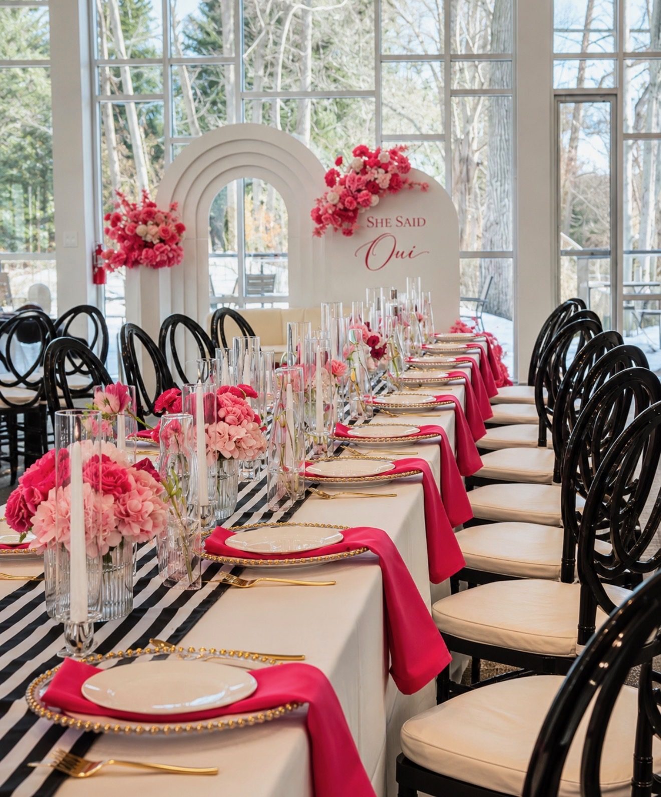 Engagement celebration table with a black-and-white striped runner, hot-pink napkins, gold-beaded chargers, and a She Said Oui arch — Creative Motion Events
